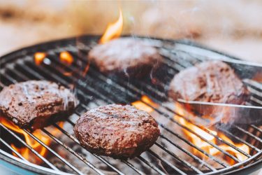 Closeup Photo of a BBQ on Backyard. Tasty Juicy Patty for Burgers. Charcoal Grill Barbecue - Traditional American Cuisine. Delicious Food for a Weekend.